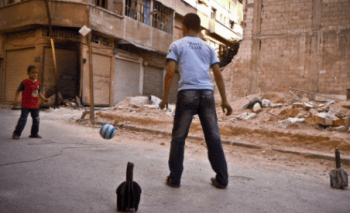 two_children_playing_football_using_old_mortars_as_goal