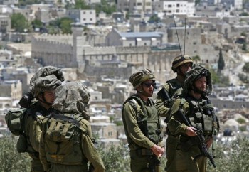 Israeli troops stand guard as Palestinia
